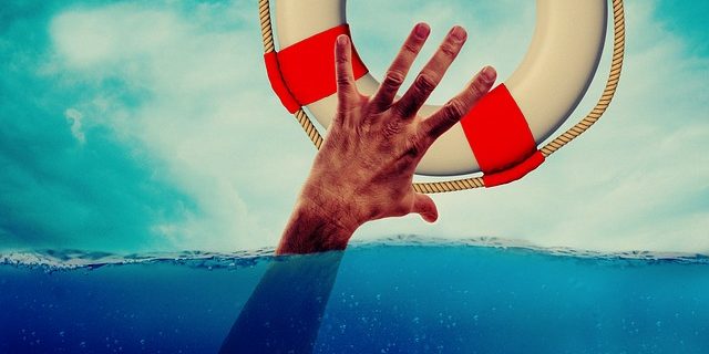 Eine Hand greift aus dem Wasser nach einem Rettungsring
