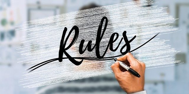 Eine Hand, die mi einem Stift das Wort "Rules" auf eine Glaswand schreibt