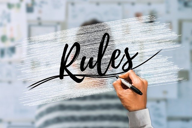 Eine Hand, die mi einem Stift das Wort "Rules" auf eine Glaswand schreibt