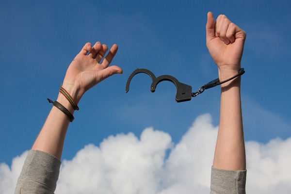 Zwei Hände mit Handschellen. An der einen Hand ist die Handschelle geschlossen. Die andere wurde davon befreit.